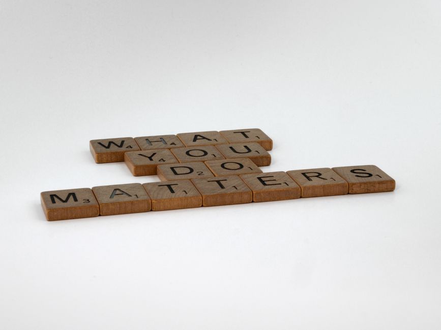 A black felt letter board with a light wooden frame is mounted on a bright yellow wall. The board displays the message 'WHAT IN THE ACTUAL HELL?' in uppercase teal letters. The image suggests an element of exaggeration or frustration, which may relate to the complexities of home relocation or moving logistics, as seen in the context of house removals and packing by Man with Van Fulwell. The lighting is even, highlighting the contrast between the dark board and the vibrant background, creating a visually clear and neutral depiction relevant to the theme of moving or handling confusing removal quotes.